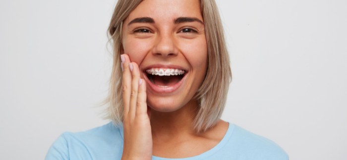 Woman with traditional braces looking into camera smiling showing her traditional braces.