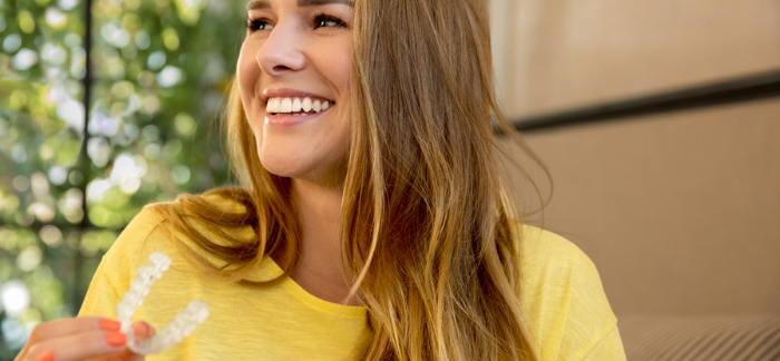 blonde woman holding her invisible aligners in Clapham 