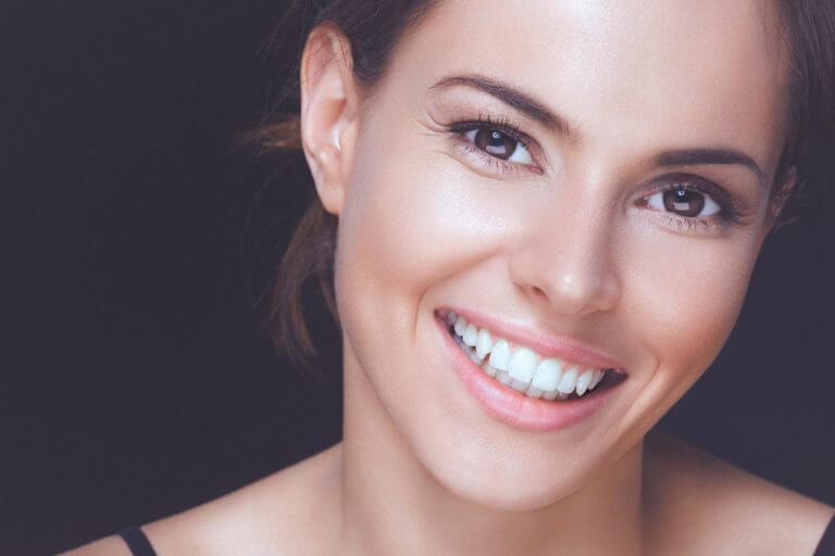 Young lady looking happy, smiling at the camera with pearly white teeth as she had been doing teeth whitening treatments.