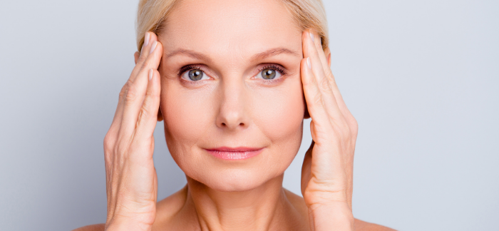 Blonde woman holding her hands up next to her head to stretch skin