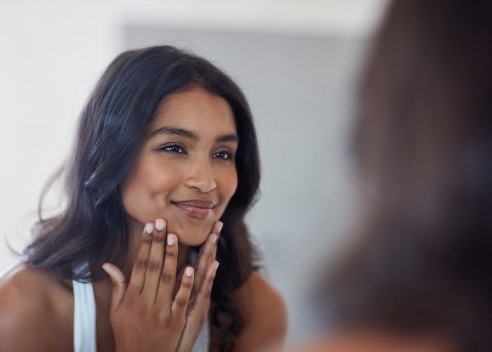 Brunette woman looking at her face in the mirror