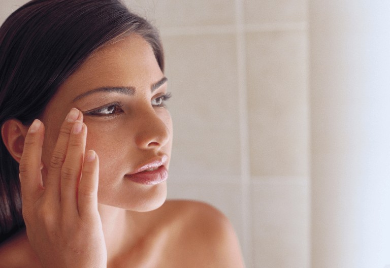 shows a Woman checking her lack of wrinkles in the mirror - Botox london