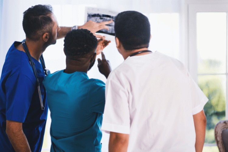 three dentists looking at a dental implant x-ray in London