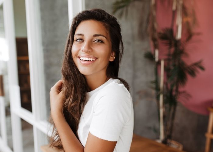 A woman with long brown hair smiling after having her white fillings replaced