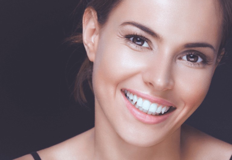 A woman smiling with white teeth after using adult braces at Crescent Lodge Dental, London
