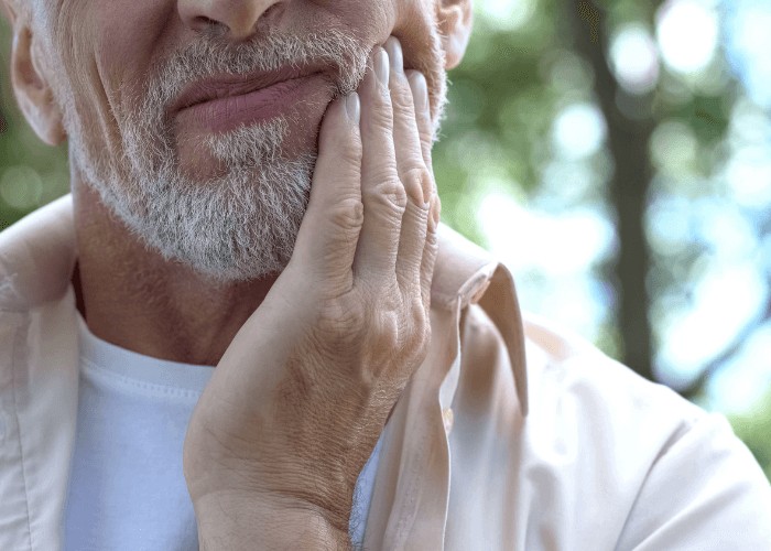 Older man in discomfort holding his mouth
