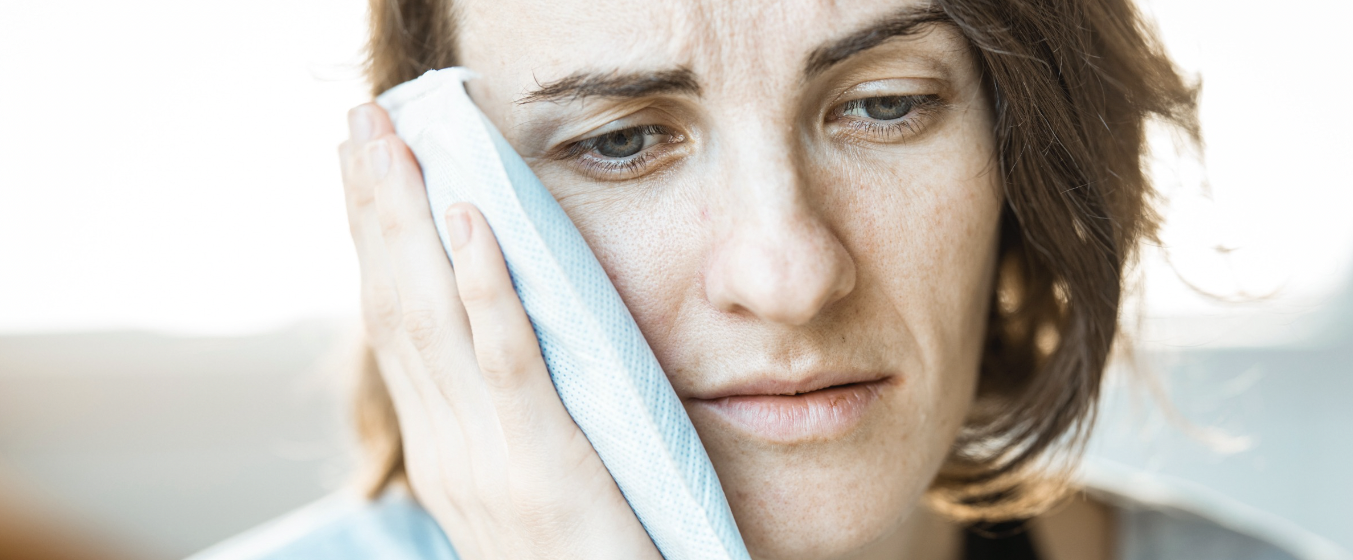 Woman with icepack on her face with dental emergency pain